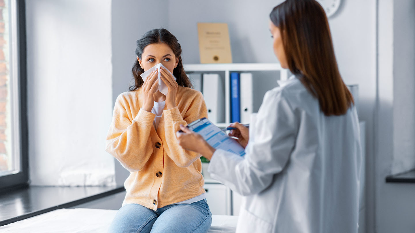 Жена со грип ја прегледува лекар.