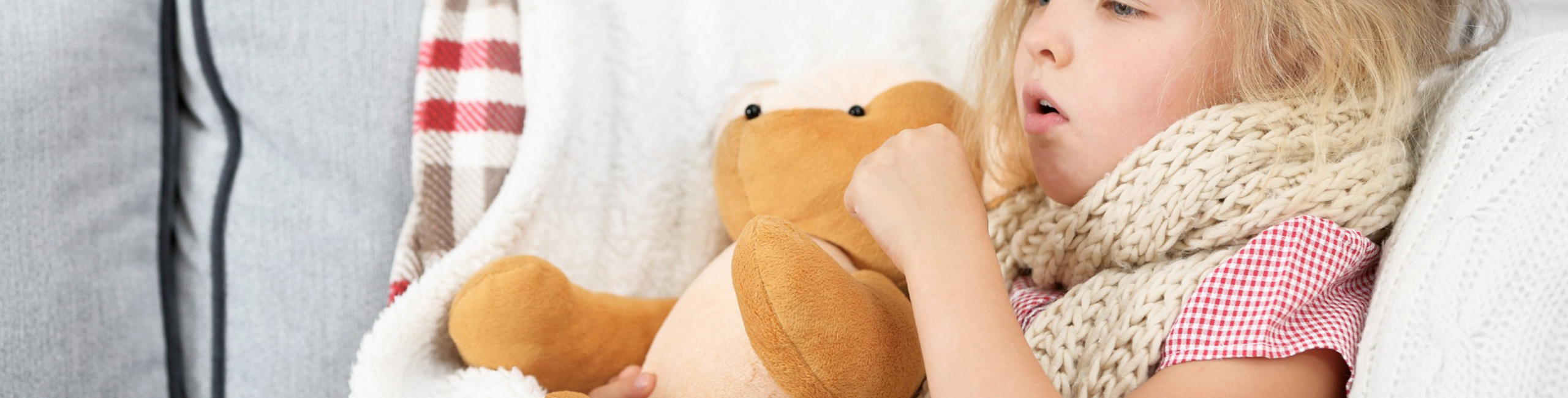 Болно девојче се држи за плишана играчка.